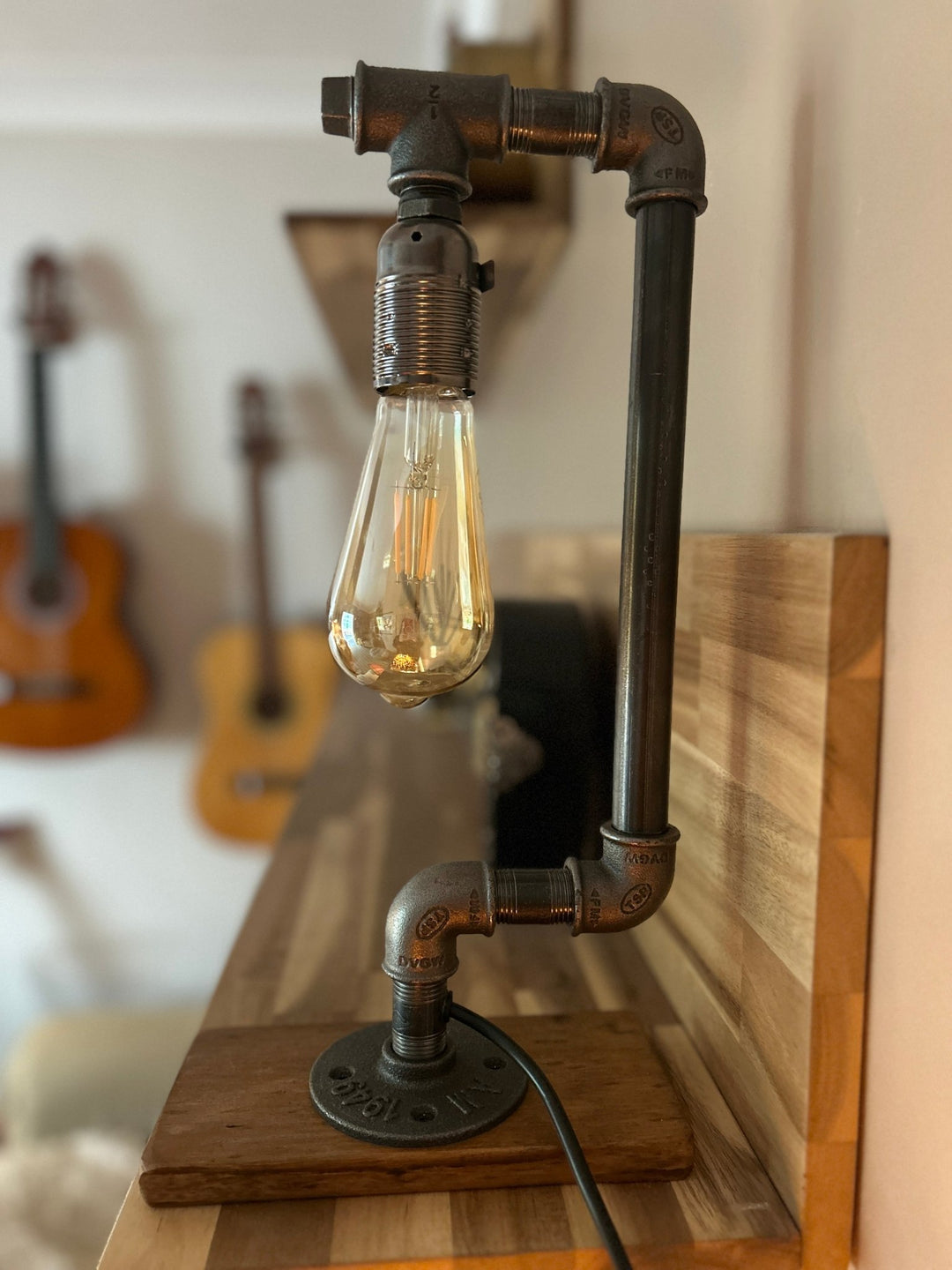 industrial style table lamp with pipe structure and wooden base, a bulb resembling a drop of water, shown in a home
