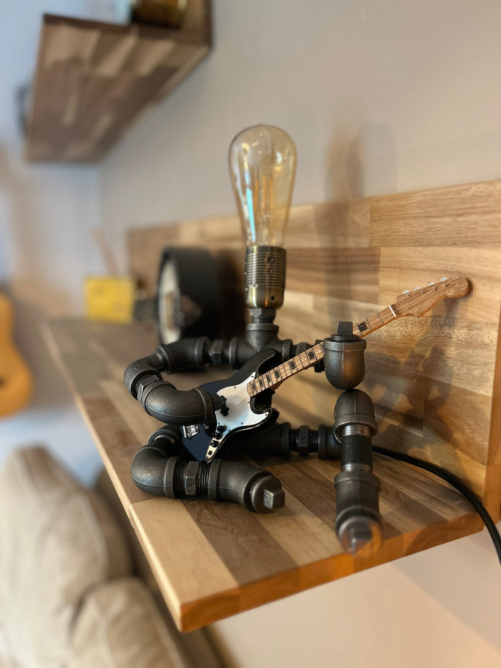 Pipework Guitar lamp holding a black electric stratocaster inspired miniature guitar
