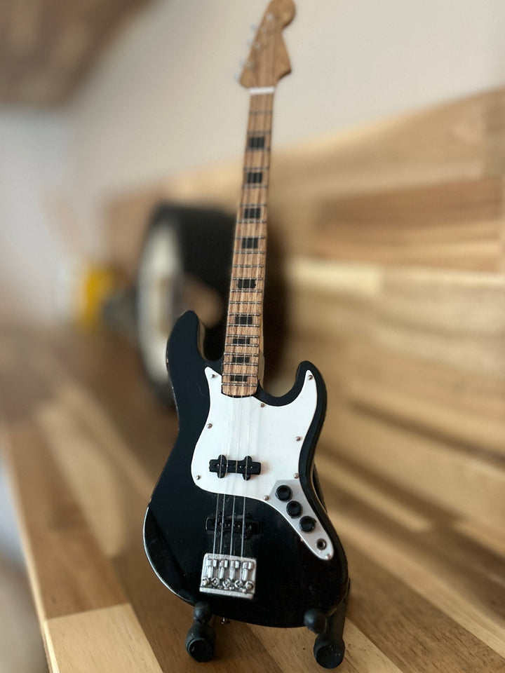 Black electric bass guitar on a wooden surface with a blurred background