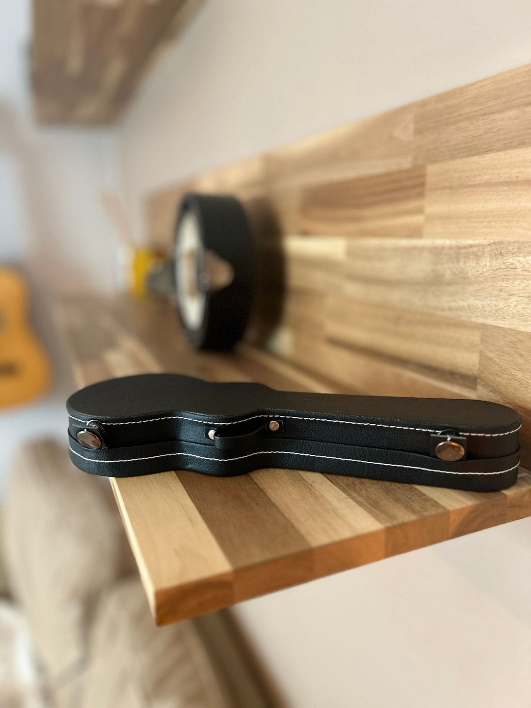 Black miniature guitar case on a wooden surface with a blurred background