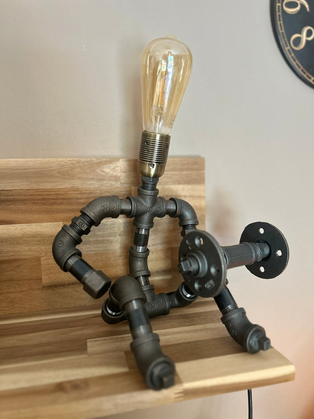 Industrial-style pipework table lamp in stance of a weightlifter with dumbbell front on