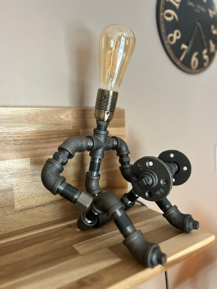 Industrial-style pipework table lamp in stance of a weightlifter with dumbbell