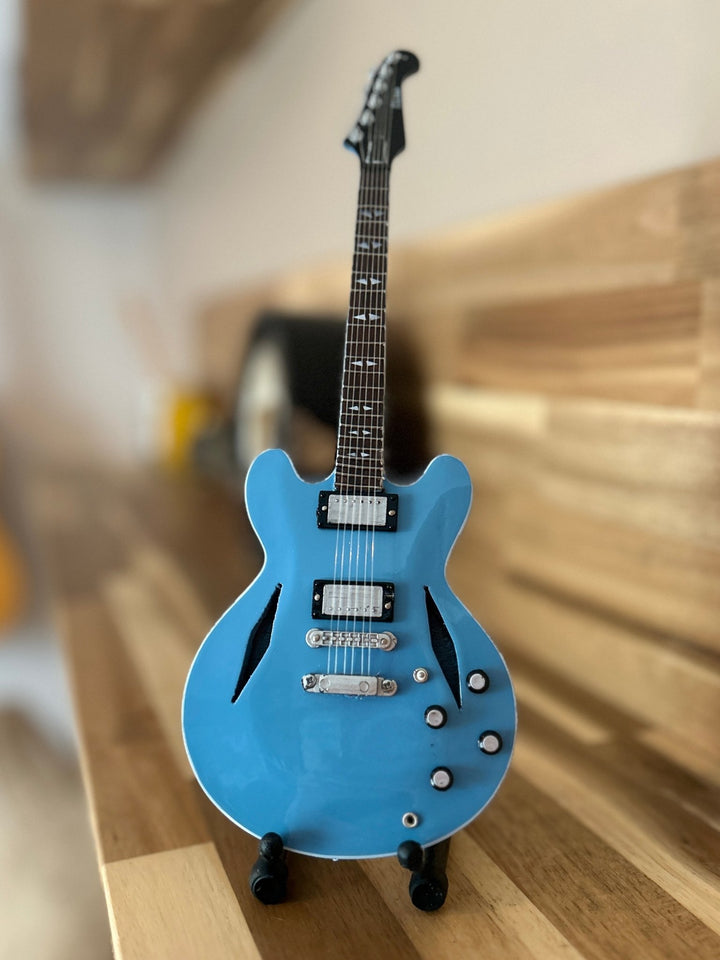 miniature Foo Fighters replica guitar on a wooden surface with a blurred background