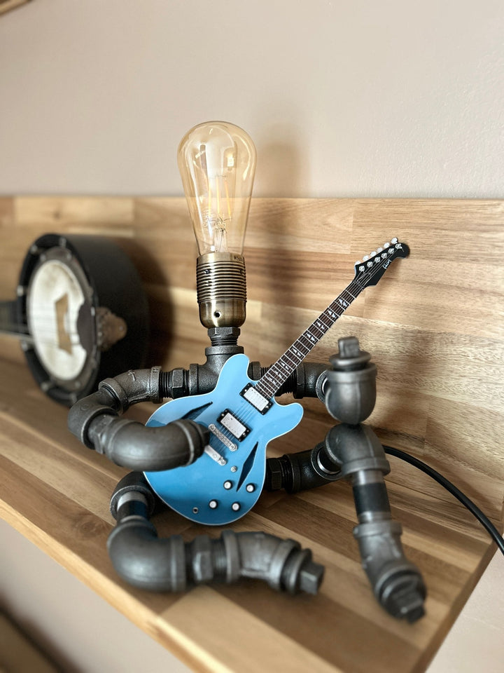 Pipework Guitar lamp holding a Slash inspired miniature guitar on wooden shelf