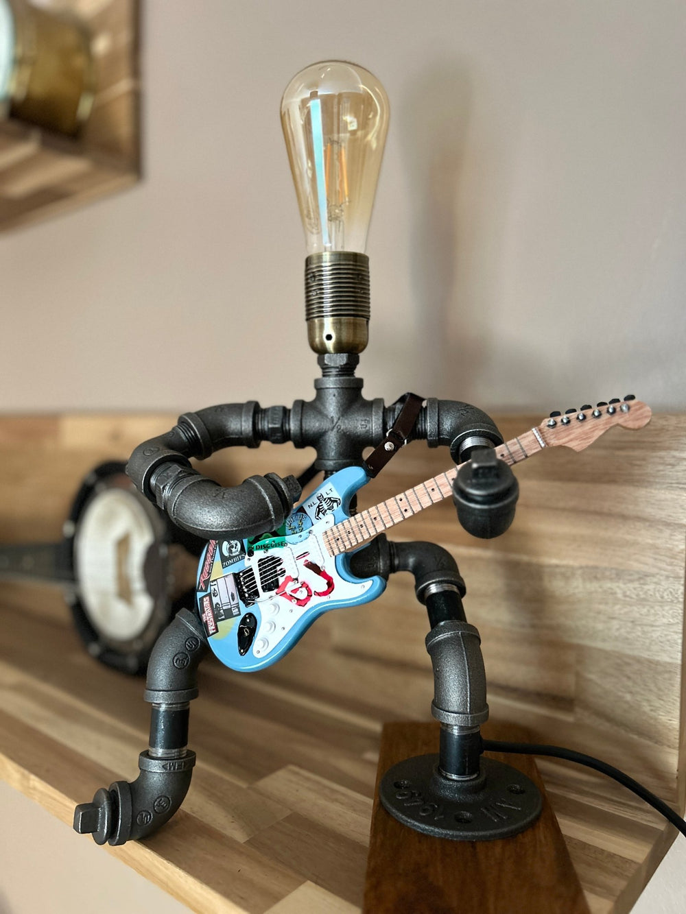 Industrial style pipework lamp in the shape of a rock guitarist with a light bulb forming the head of the player