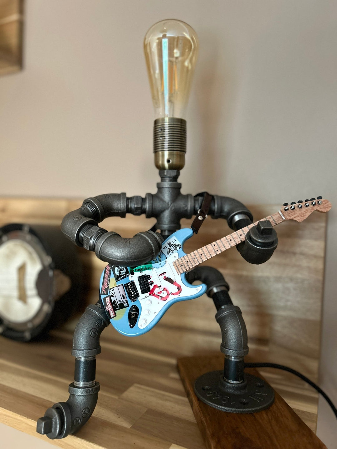 Industrial style pipework lamp in the shape of a rock guitarist with a miniature replica Green Day guitar