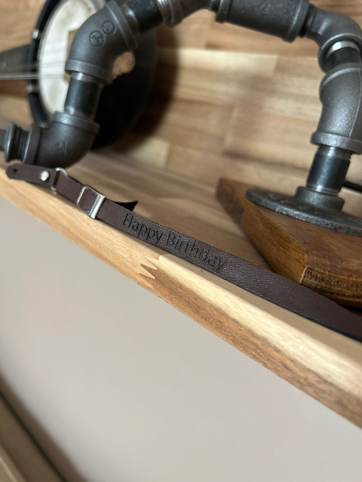 Close-up of a mini guitar strap at the base of a lamp with the words happy birthday embossed on it