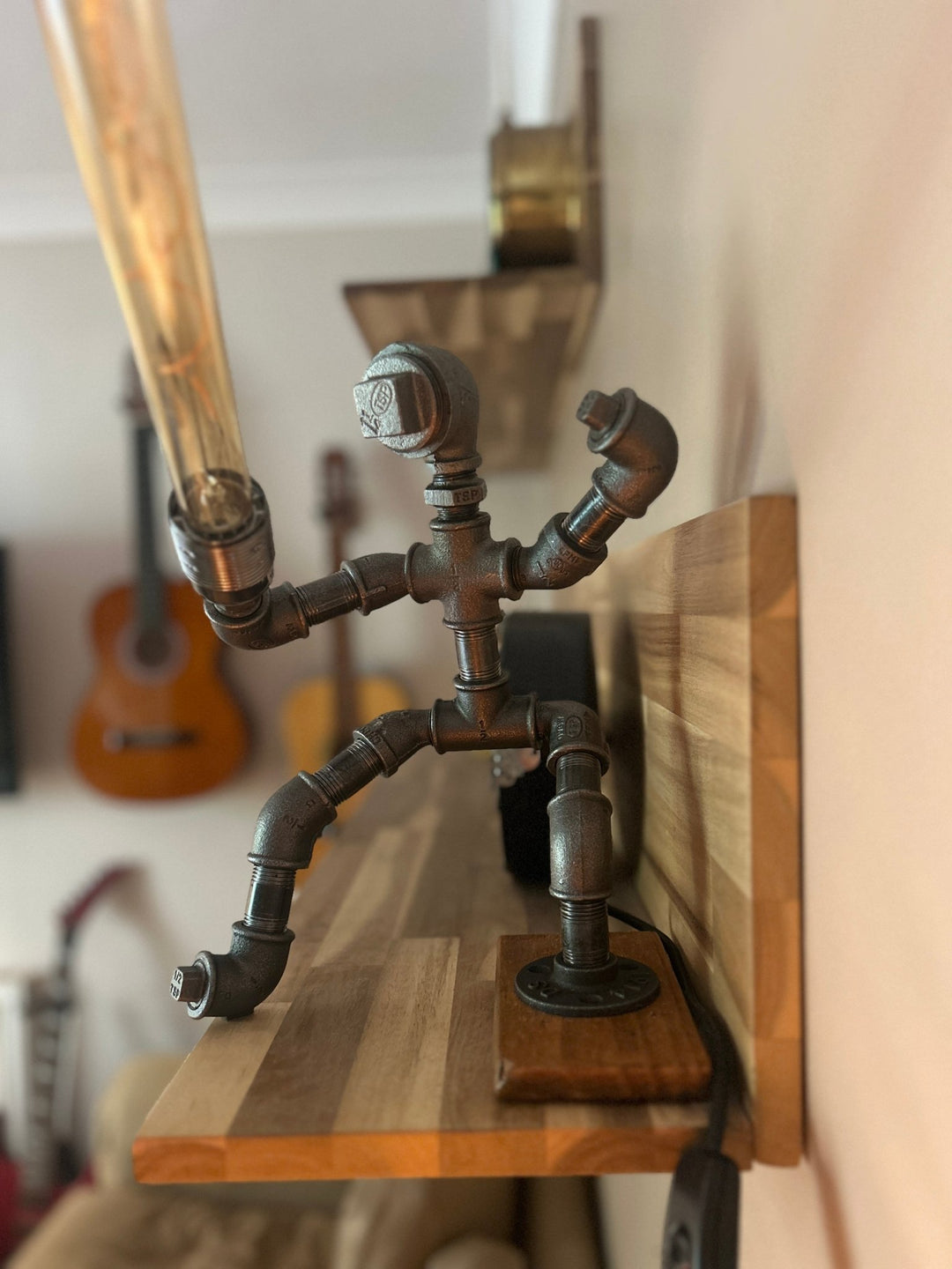 Decorative pipework lamp in the stance of a Jedi Knight holding a long bulb to imitate a lightsaber shown on a shelf