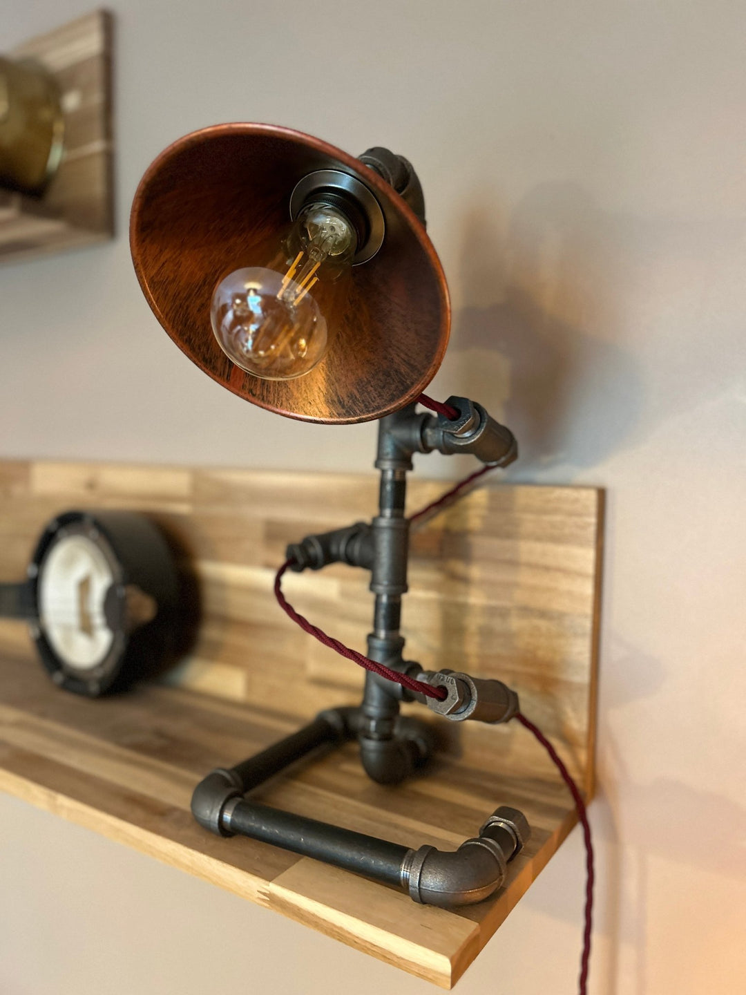 Bulb detail of Pipework Lamp with braided burgundy cord spiralling around the lamp 