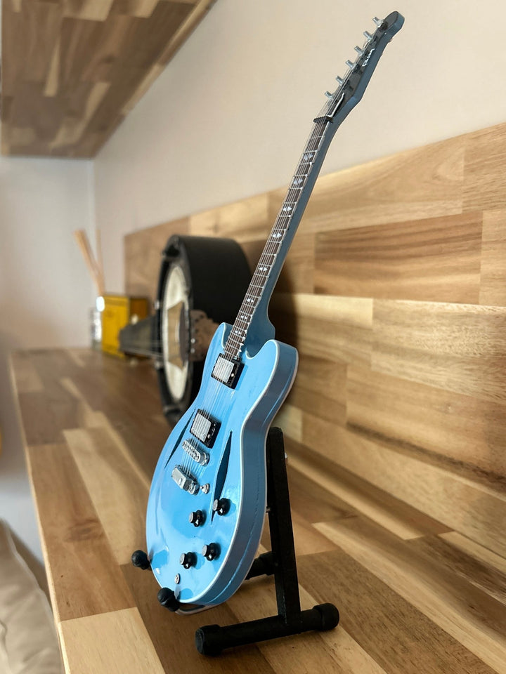 miniature Foo Fighters replica guitar on a wooden surface on a stand