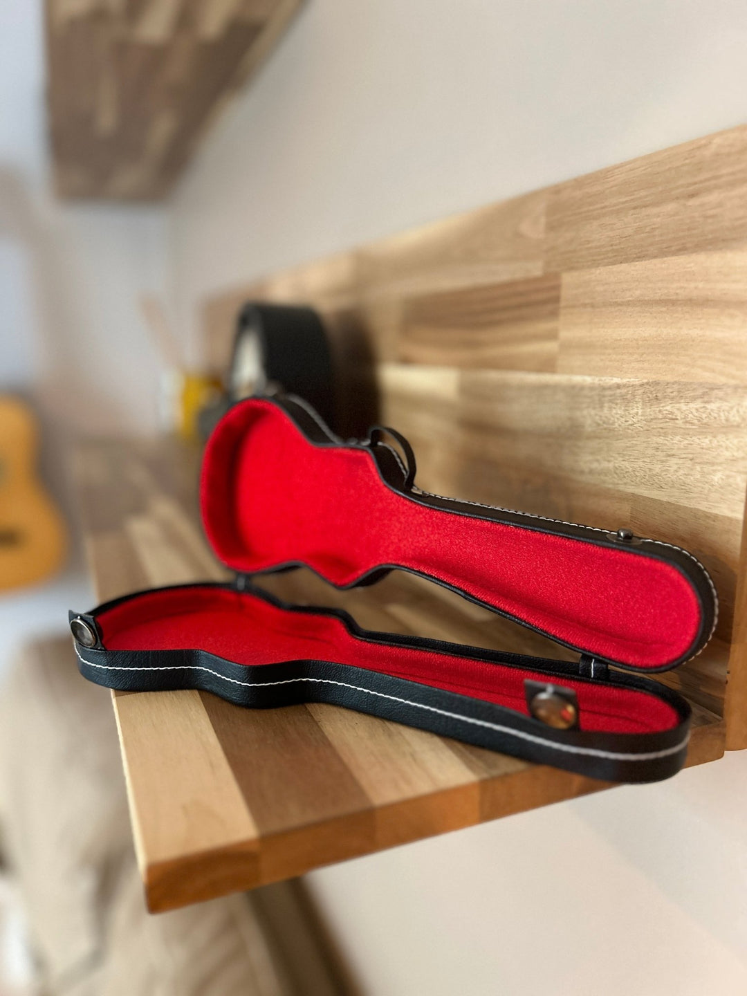 miniature guitar case with black trim open on a wooden shelf
