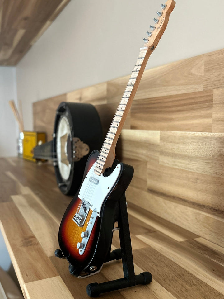 miniature Radionhead replica guitar on a wooden surface on a stand
