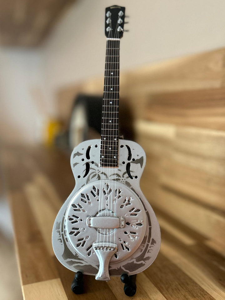 Miniature Resonator guitar with decorative body on a wooden surface