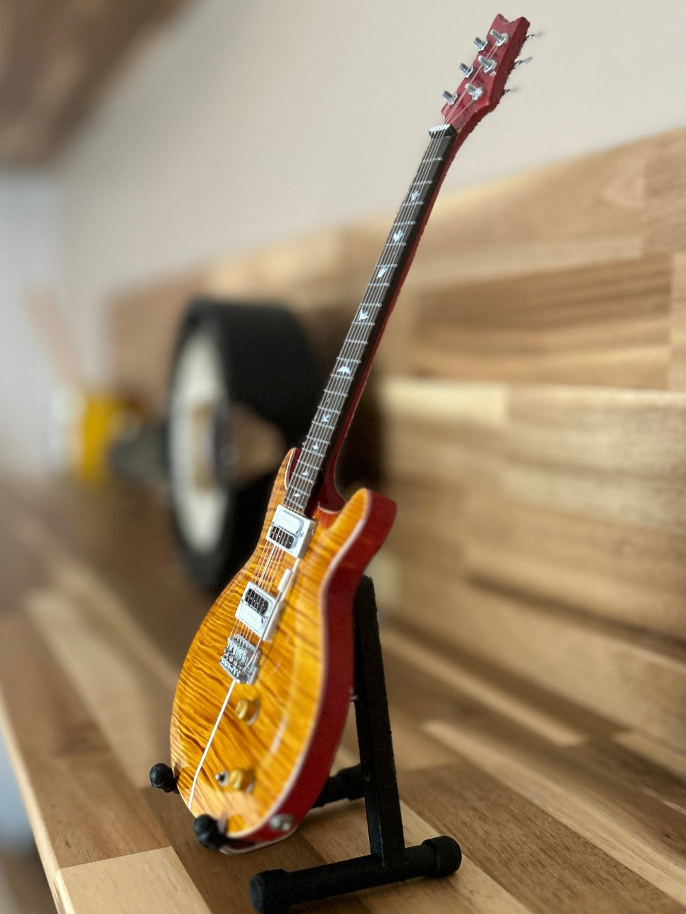 miniature Radiohead replica guitar on a wooden surface on a stand