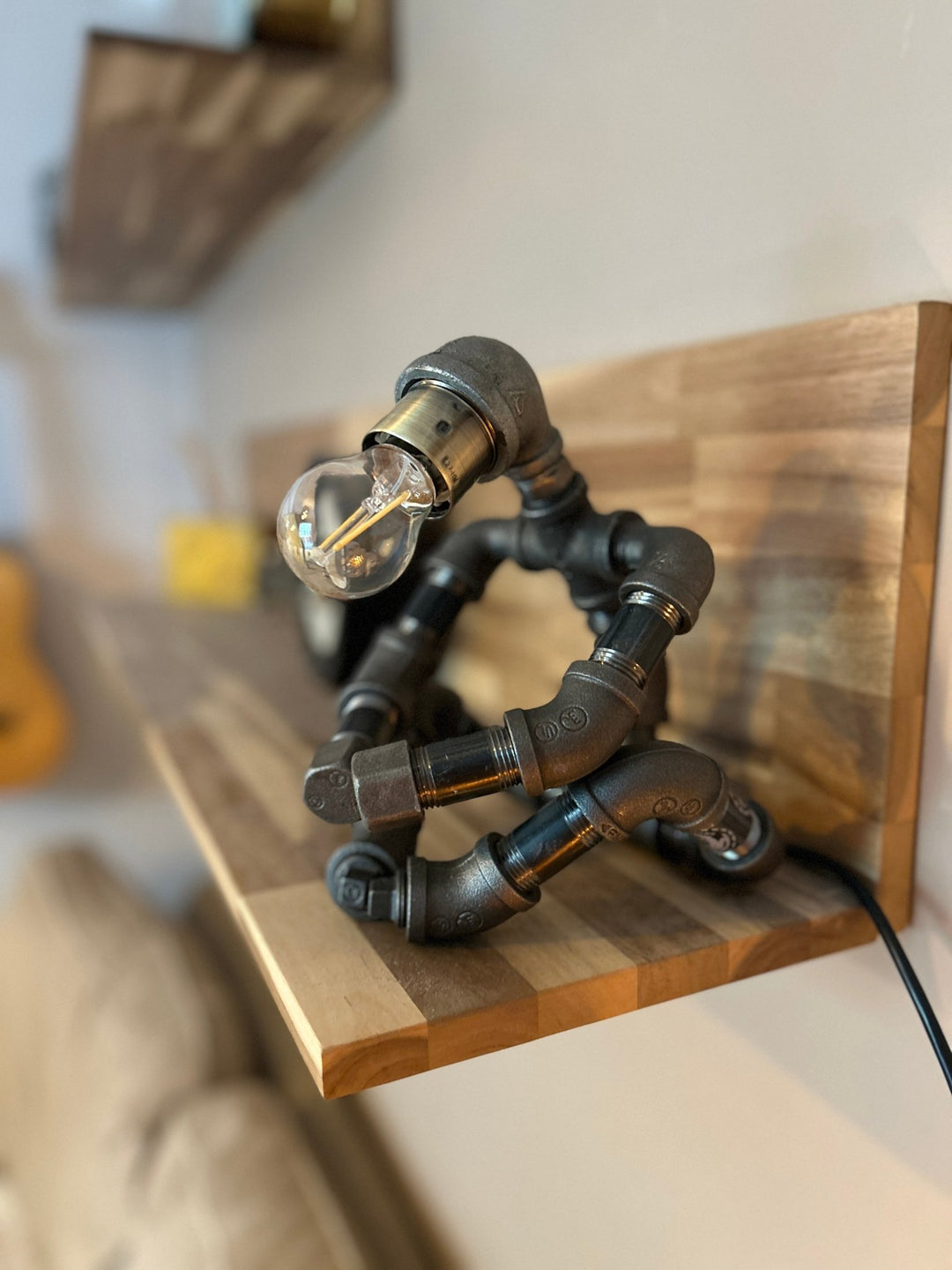 Industrial-style pipework robot lamp on a wooden shelf