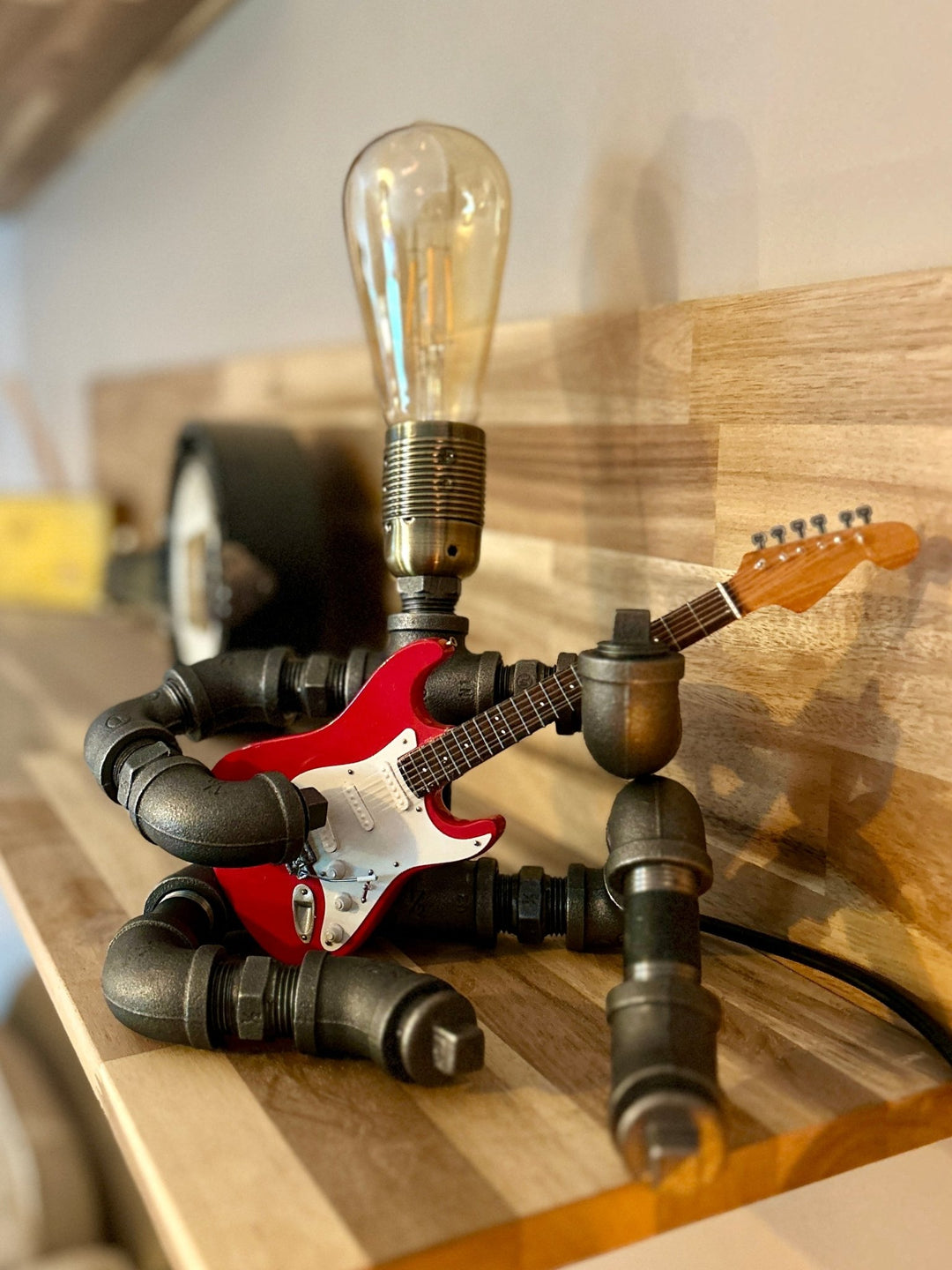 Pipework Guitar lamp holding a red electric stratocaster inspired miniature guitar
