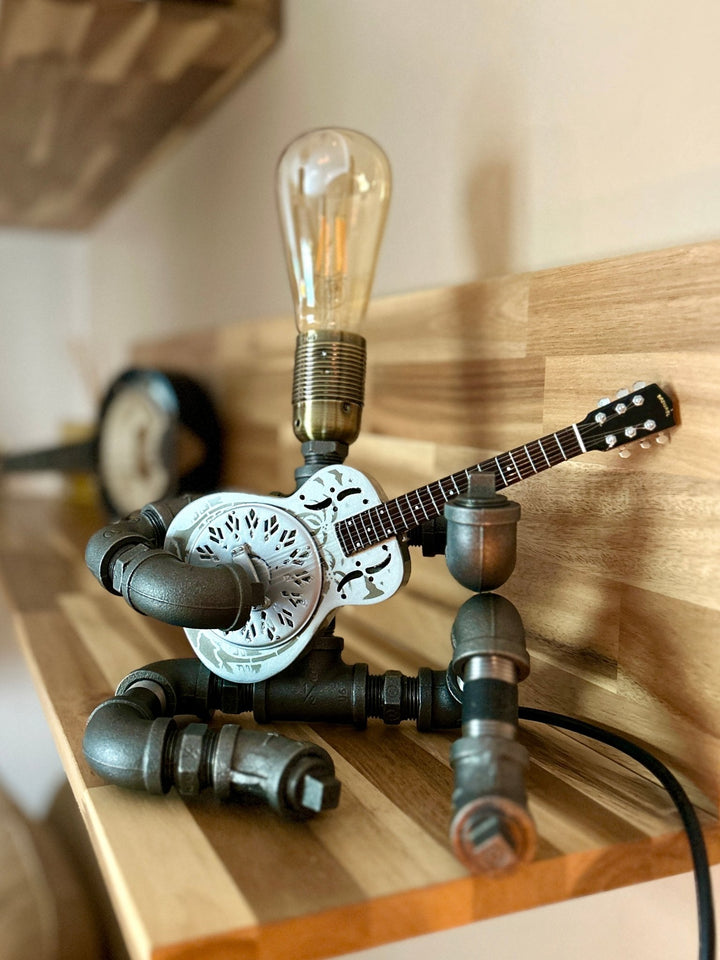 Pipework Guitar lamp holding a resonator inspired miniature guitar