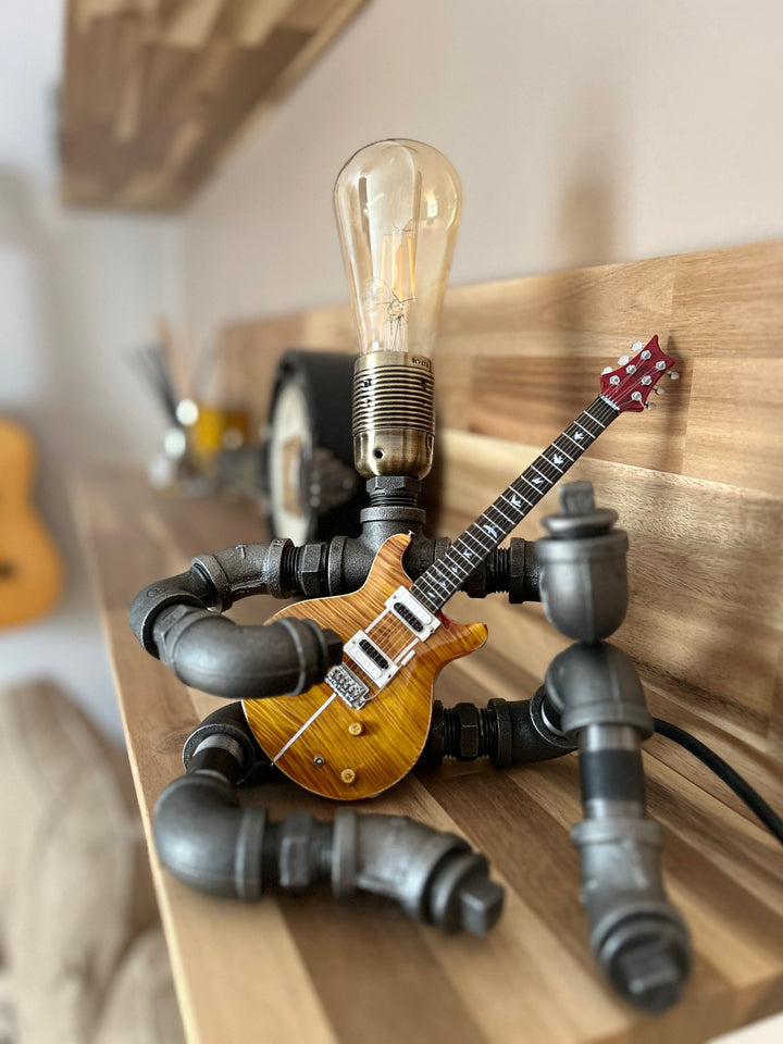 Pipework Guitar lamp holding a Santana inspired miniature guitar on a shelf