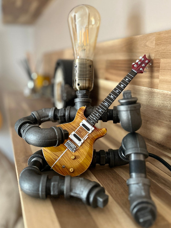 Pipework Guitar lamp holding a Santana inspired miniature guitar