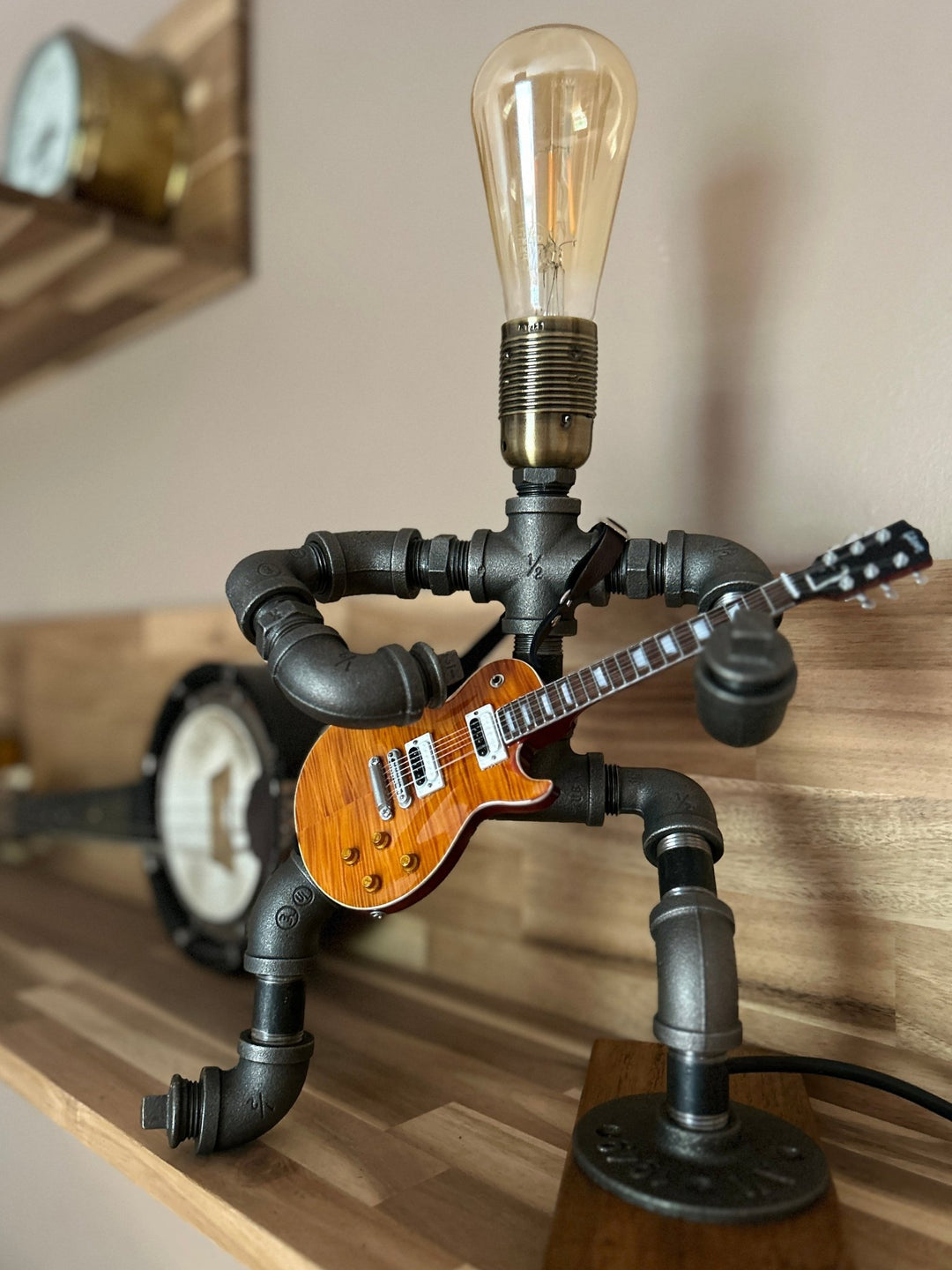 Guitar-shaped lamp made of pipe with a light bulb on a wooden surface