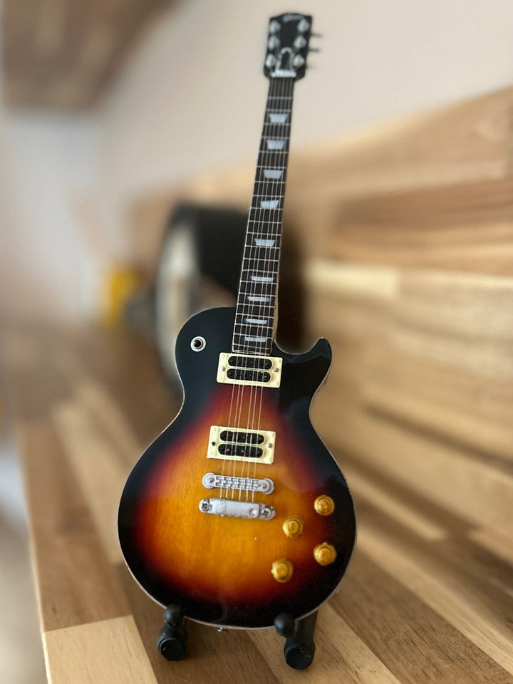 miniature Slash replica guitar on a wooden surface with a blurred background