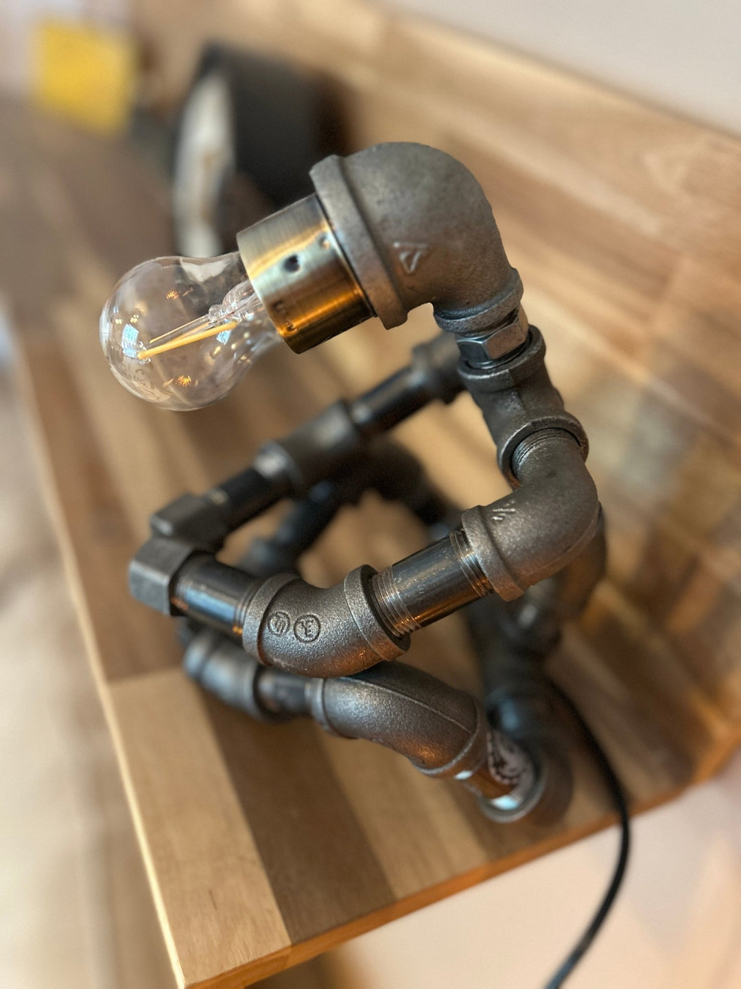 Industrial-style robot pipe lamp on a wooden shelf view from above
