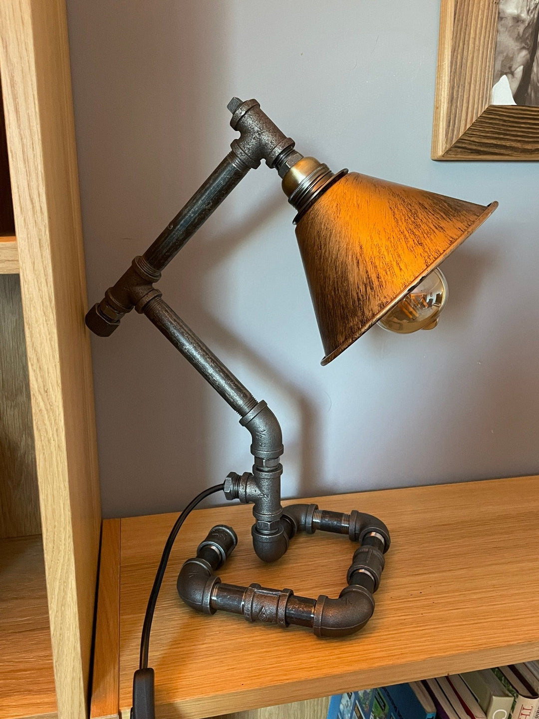 Industrial pipework lamp on a wooden bookcase side on