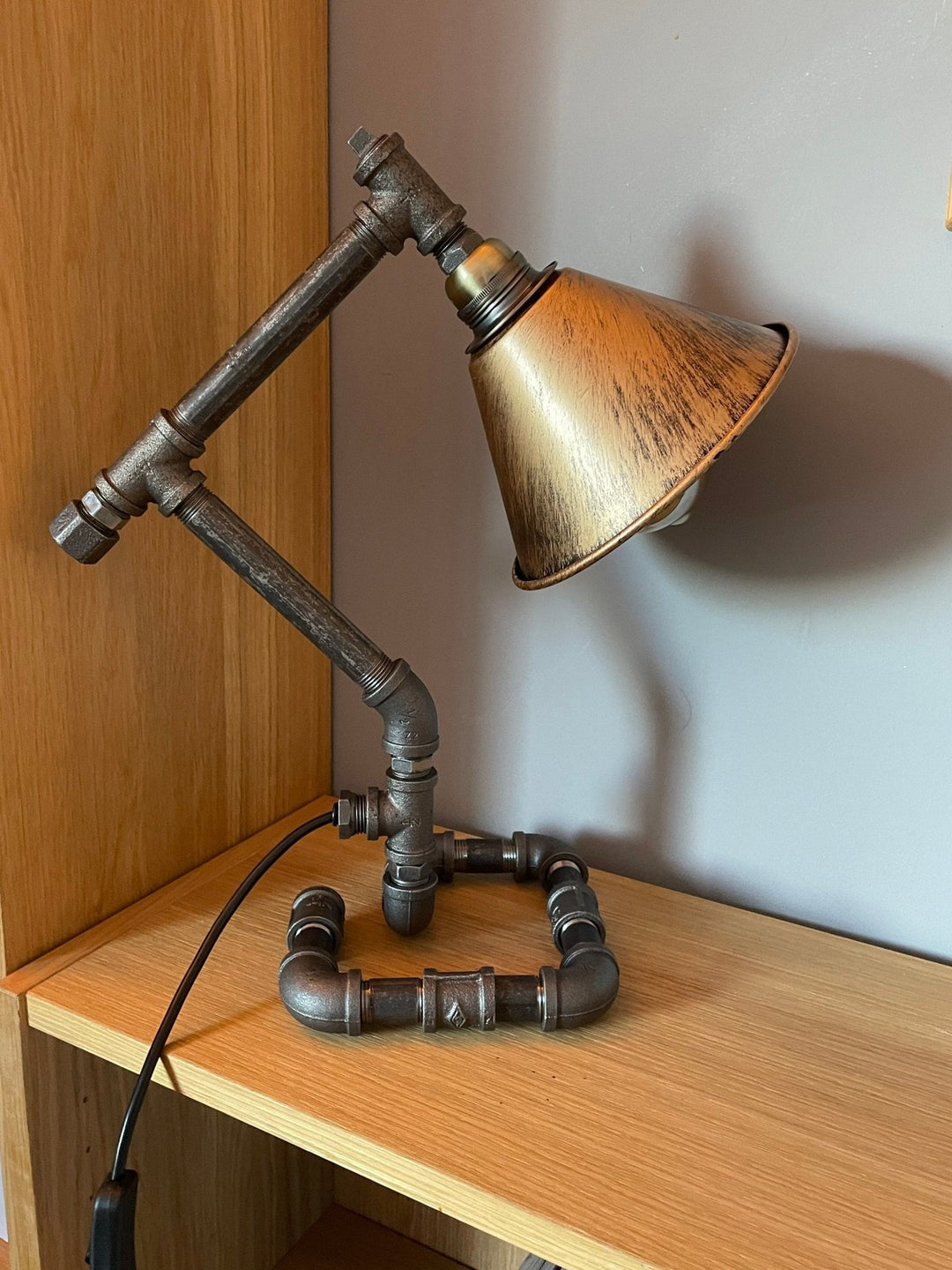Industrial-style lamp with metal pipe design on a wooden surface.