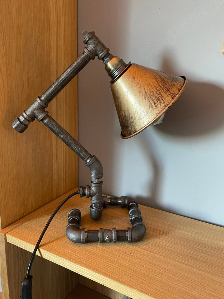 Industrial-style lamp with metal pipe design on a wooden surface.